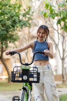 Happy young asian woman in casual clothes enjoy riding bicycle at the park for recreation.