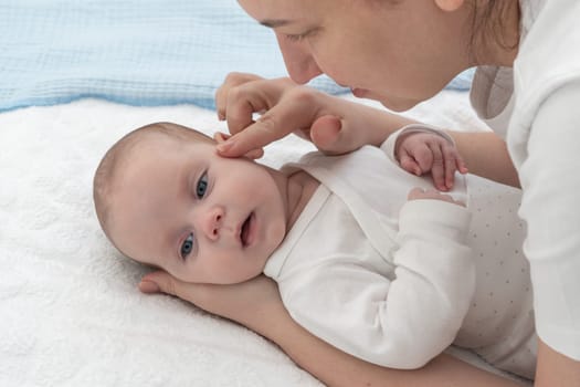 The mother gently touches the baby's head with her finger