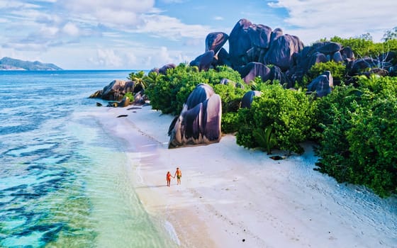 Anse Source d'Argent beach, La Digue Island, Seyshelles, Drone aerial view of La Digue Seychelles bird eye view.of tropical Island, couple men and woman walking at the beach during sunset at a luxury vacation