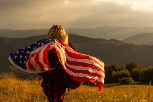 Young woman holding American flag on sky background.