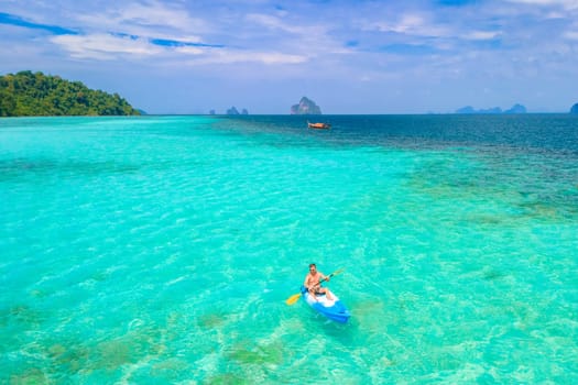 Young man in a kayak at the bleu turqouse colored ocean of Koh Kradan a tropical island with a coral reef in the ocean, Koh Kradan Trang Thailand