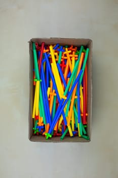 Set of multi colored straw constructor in cardboard box on the table, a flexible constructor made of plastic tubes