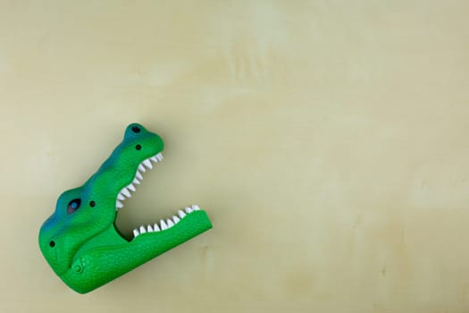 Dinosaur with open mouth with sharp teeth on the table, children plastic toy, kid play space