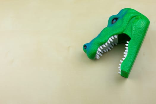 Children toy of an extinct animal lying on the table, green dinosaur with an open mouth, concept of a children toy