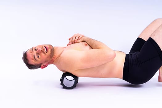 Athlete massaging and stretching iliotibial ban muscle with a foam roller.