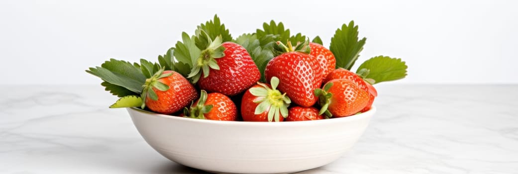 A white bowl filled with lots of ripe strawberries