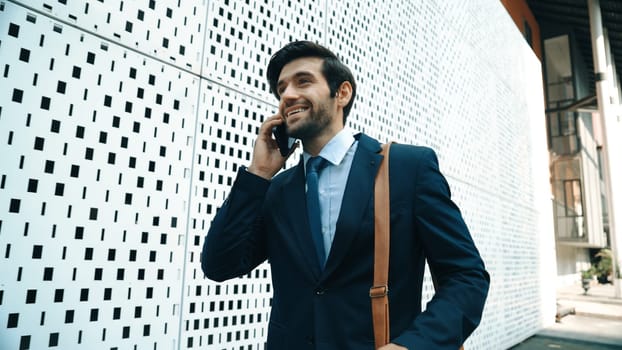 Smart business man using phone to talking about business investment. Happy manager walking at street while talking on smart phone to discuss business plan or marketing strategy or working. Exultant.