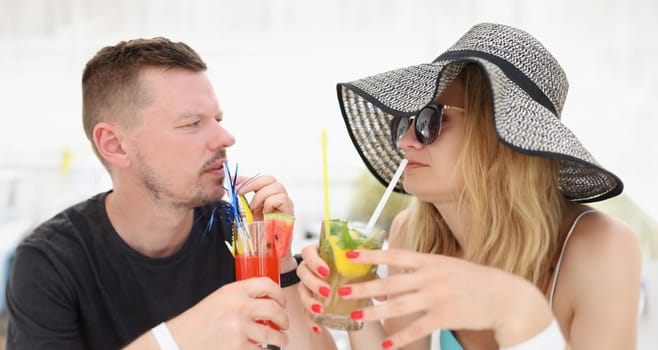 A man and a woman on vacation drink tropical cocktails, close-up. Romantic relationship at the resort