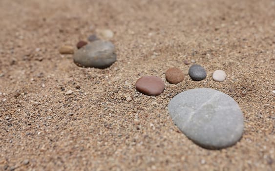 Footprint of stones in the sand, close-up. Wallpaper concept vacation at sea, borders open, beach season