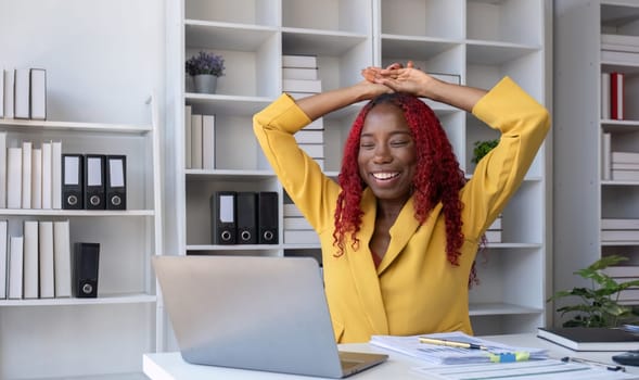 African American businesswoman sitting happy doing accounting and finance work on her desk in the office..