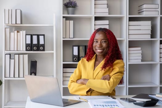 African American businesswoman sitting happy doing accounting and finance work on her desk in the office..