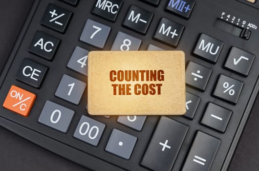 Financial concept. There is a sign on the calculator that says - Counting the cost