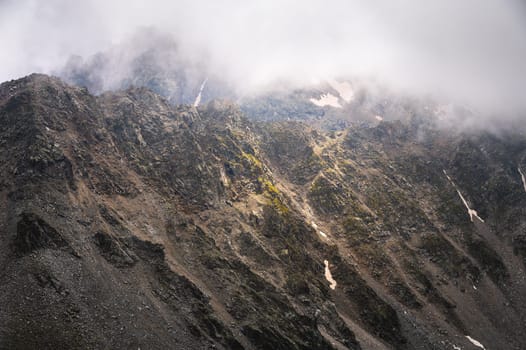 Fog and cold on one of the peaks in the mountains. Mystical atmosphere over the mountain range.