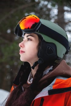 Skier, skiing, winter sports, female skier portrait. A beautiful girl stands against the backdrop of snow-capped mountains and looks to the side, freeride.