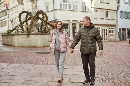 Loving couple of tourists walking around old town. Man woman couple walking europe old town Germany. Couple of lovers leisurely stroll in the cool autumn morning on the streets of a BIETIGHEIM-BISSINGEN (Germany). The guy holds his wife. Vacation, autumn, holiday. Couple Walking in Europe's Old Town