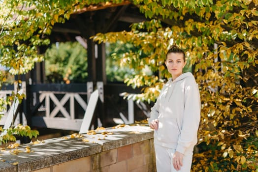 Beautiful elegant woman standing in a park in autumn. autumn yellow leaves. Portrait of joyful woman in park during fall. Happy girl with yellow leaves outdoor. Beauty Romantic Girl Outdoors enjoying nature. Beautiful autumn model with waving glow hair.Sun light on sunset.Warm toned art work. Portrait of romantic female