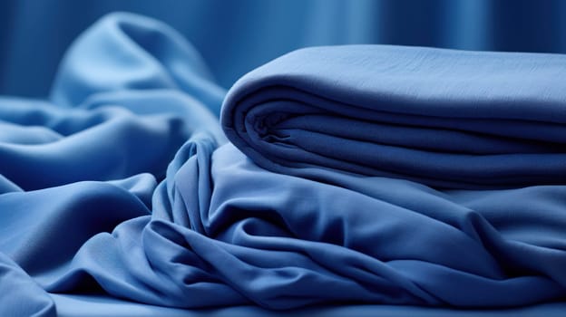 A pile of folded blue cloth on a bed with some pillows