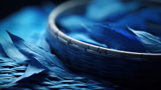 A basket of blue leaves on a woven mat with some straw