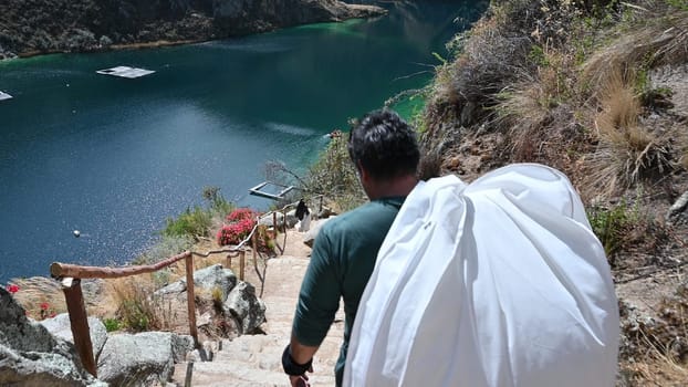 Young man hiker descending mountain trail. Hiker walking downwards towards lake on a mountain trail. Hiking fit man walking in nature, tracking shot