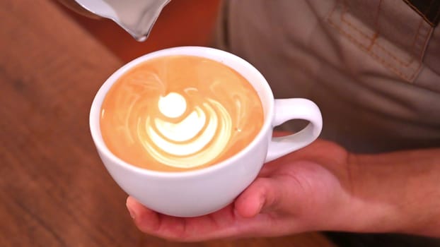 Barista pouring milk making a coffee latte art. People pour milk to making latte art coffee at cafe or coffe shop