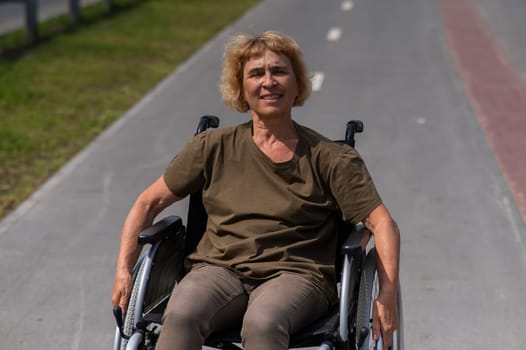 Happy elderly woman on a wheelchair rides along a bike path