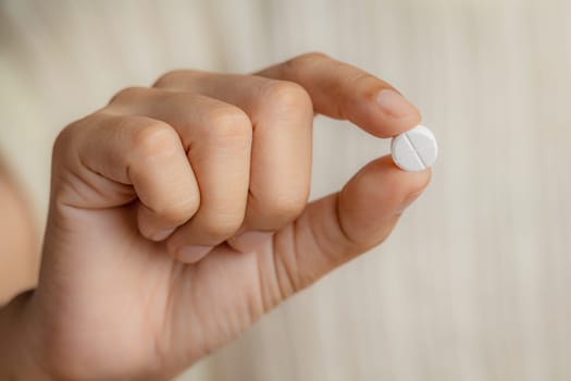 Close up of a female hand holding a pill for medical and healthcare concept