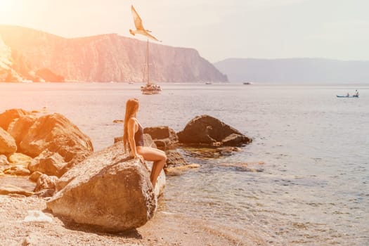 Woman travel sea. Young Happy woman in a long red dress posing on a beach near the sea on background of volcanic rocks, like in Iceland, sharing travel adventure journey