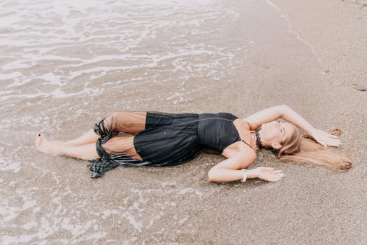 Woman travel sea. Young Happy woman in a long red dress posing on a beach near the sea on background of volcanic rocks, like in Iceland, sharing travel adventure journey