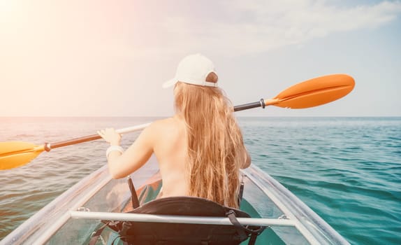 Woman in kayak back view. Happy young woman with long hair floating in transparent kayak on the crystal clear sea. Summer holiday vacation and cheerful female people having fun on the boat.