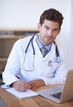 Doctor, laptop and notebook with pen at desk for telehealth, appointment or patient report in office. Man, technology and writing on paper for planning, communication or health insurance in hospital.