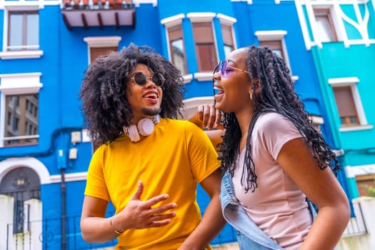 Close-up low angle view portrait of a cool african couple laughing talking in a colorful street