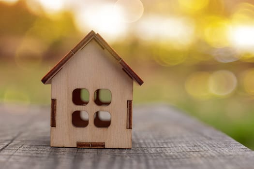 small wooden toy house stand on a wooden table on the background of yellow autumn nature. Copy space. Close up