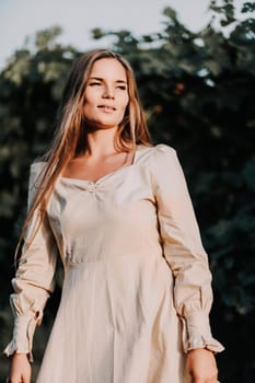 Woman stands in front of vineyard. She is wearing a light dress and posing for a photo. Travel concept to different countries.