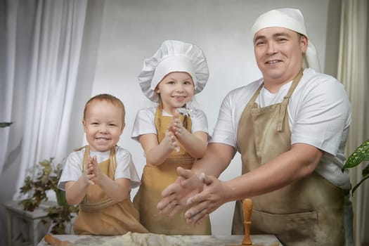Cute oriental family with father, daughter, son cooking in kitchen on Ramadan, Kurban-Bairam, Eid al-Adha. Funny family at a cook photo shoot. Pancakes, pastries, Maslenitsa, Easter