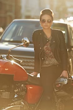 Bike, leather and woman in city with sunglasses for travel, transport or road trip as rebel. Fashion, street and model with attitude on classic or vintage motorcycle for transportation or journey.