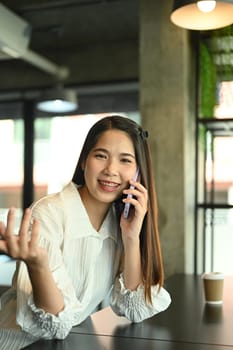 Portrait of smiling businesswoman having pleased phone conversation at coffee shop.