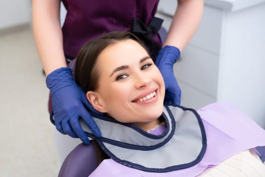 Dentist assistant wears shield for neck protection to patient before x ray procedure of tooth