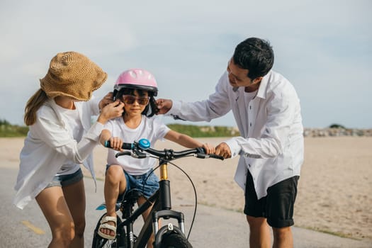 A memorable summer day on sandy beach as parents teach their children joy of bicycle riding. Smiles safety helmets and freedom of cycling make this delightful family moment filled with carefree fun.