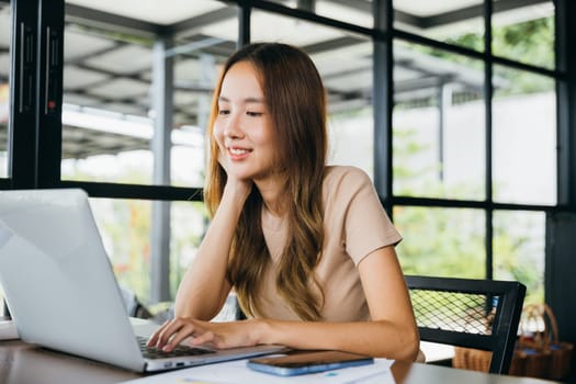 Happy businesswoman smiling sitting alone at cafe desk with laptop computer she looking out of window, portrait of beautiful woman smile in coffee shop in morning, freelance lifestyle