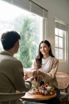 Romantic young asian couple embracing giving present in living room at home. Fall in love. Valentine concept.