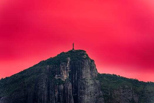 Imposing Christ statue in Rio de Janeiro stands on a cliff under a blood-red sky, symbolizing a perilous future.
