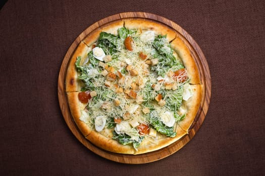 A delicious round pizza with salad, tomatoes, cheese, croutons on wooden board. Isolated on brown background, perfect for food blogs, restaurant websites, social media.