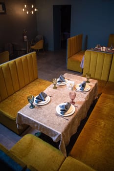 This image showcases an elegant restaurant interior with a table set for four, yellow booths, and ambient lighting, ideal for fine dining or a romantic dinner for two.