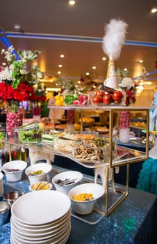 Indulge in a delectable array of salads, vegetables, and snacks, artfully presented on a buffet table. Perfect for events, parties, or gatherings. Isolated on blue background.