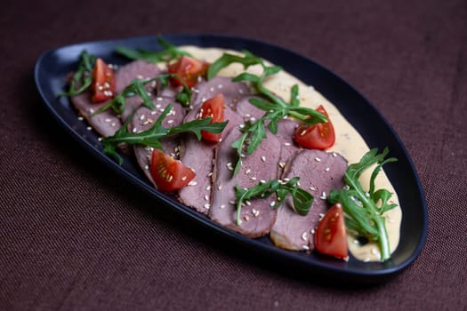 Savor the succulent flavors of pan-seared duck breast served with a vibrant arugula salad topped with cherry tomatoes, sprinkled with toasted sesame seeds, and drizzled with a luscious creamy sauce.