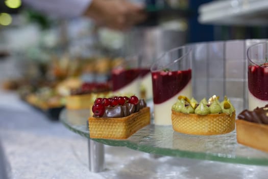 Variety of sweet and savory canapes and desserts displayed on glass shelf. Canapes topped with ingredients like caviar, salmon, and vegetables. Desserts include tarts, cakes, and pastries.