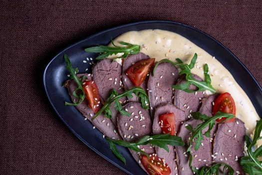 Savor the succulent flavors of pan-seared duck breast served with a vibrant arugula salad topped with cherry tomatoes, sprinkled with toasted sesame seeds, and drizzled with a luscious creamy sauce.