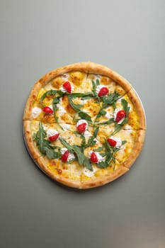 A delicious pizza with strawberries, cream cheese, and arugula on a white plate. The pizza is isolated on a green background. The pizza is perfect for a summer party or a picnic.