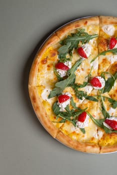 Freshly baked pizza with strawberries, cream cheese and arugula on a white plate. view from above.