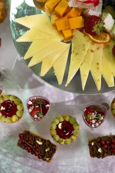 Variety of sweet and savory canapes and desserts displayed on glass shelf. Canapes topped with ingredients like caviar, salmon, and vegetables. Desserts include tarts, cakes, and pastries.